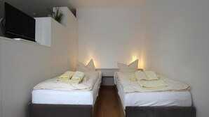 A modern room with two beds, each with a pillow and a folded towel. - Ferienwohnung in Westerland auf Sylt (Sylt)