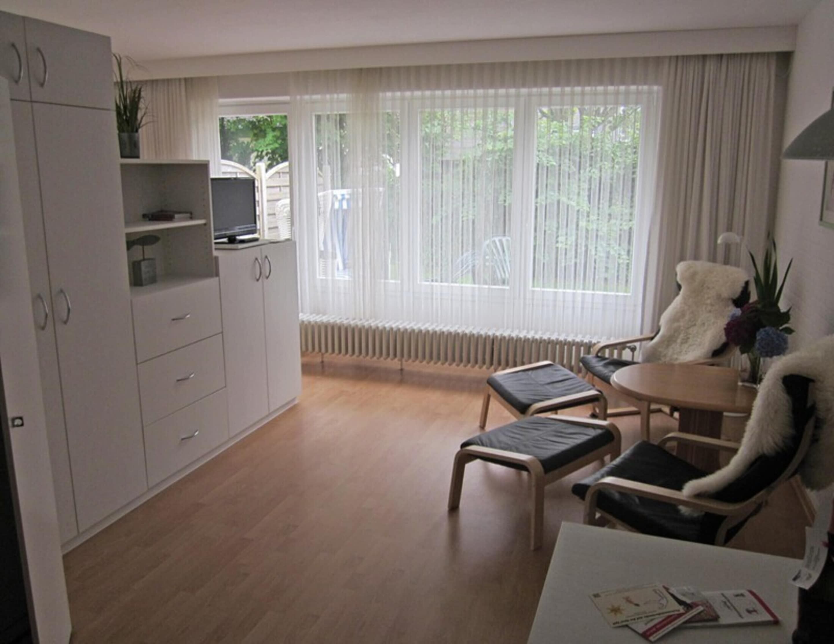 Una sala de estar moderna con comedor, un armario blanco y vistas amplias desde grandes ventanales.