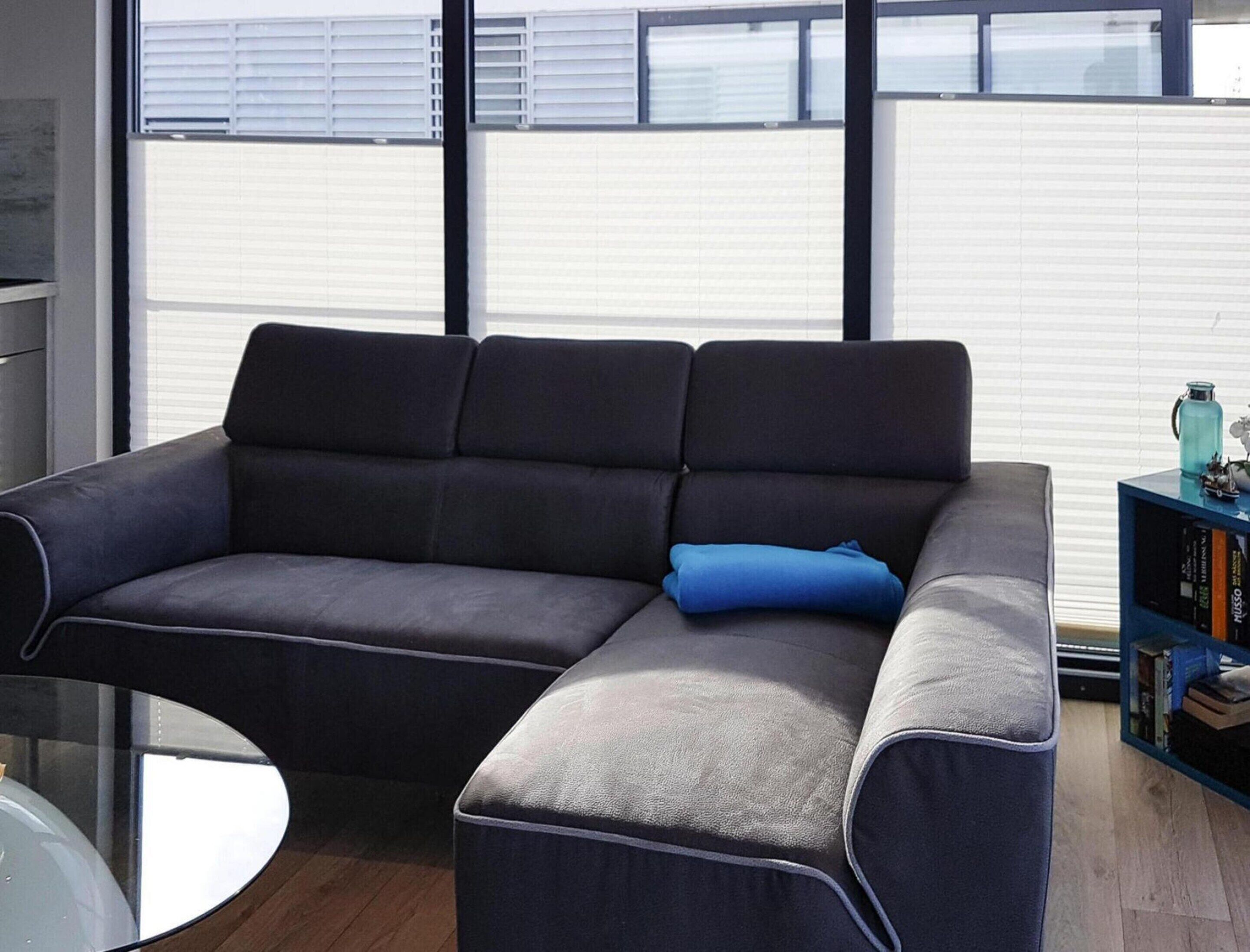 A modern living room with a grey sectional sofa, a small round table, and a bookshelf.