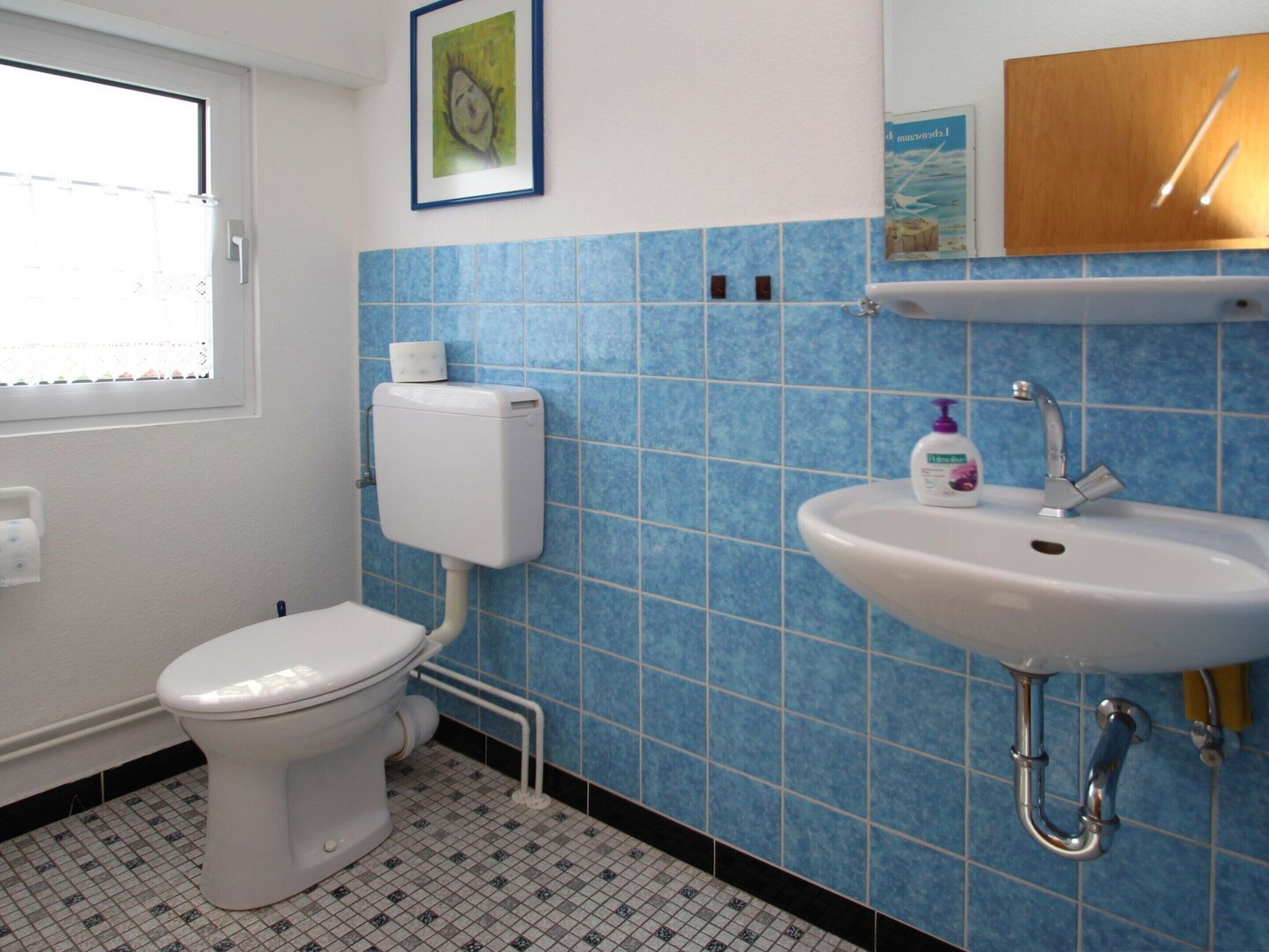 Ein Badezimmer mit Toilette, Waschbecken und blauen Fliesenwänden.