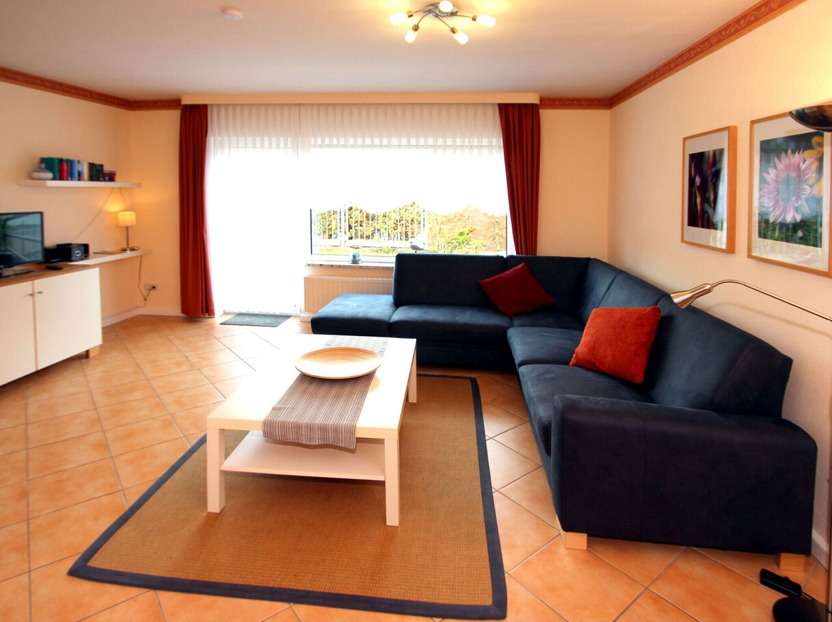 A living room with a sofa, a coffee table, a TV, and a window with curtains.