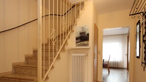 A staircase with white railings leading to a landing with a radiator and a framed picture. - Gemuetliches Reihenhaus mit Garten (Dornum)