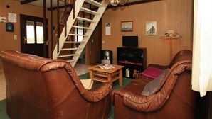 A living room with two brown leather sofas, a wooden coffee table, a television, and a staircase. - Bootshaus in Teterow - Formerly TUI (Teterow)