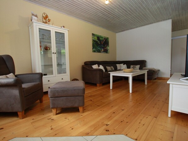 A living room with a brown leather sofa, a white cabinet, and a wooden floor. - Ferienhaus in Clausthal-zellerfeld mit Terrasse (Clausthal-Zellerfeld)