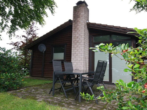 Une cheminée en briques, une antenne parabolique et une terrasse avec des chaises.