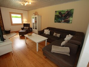 A living room with a brown sofa, white table, and a cabinet with glass doors.