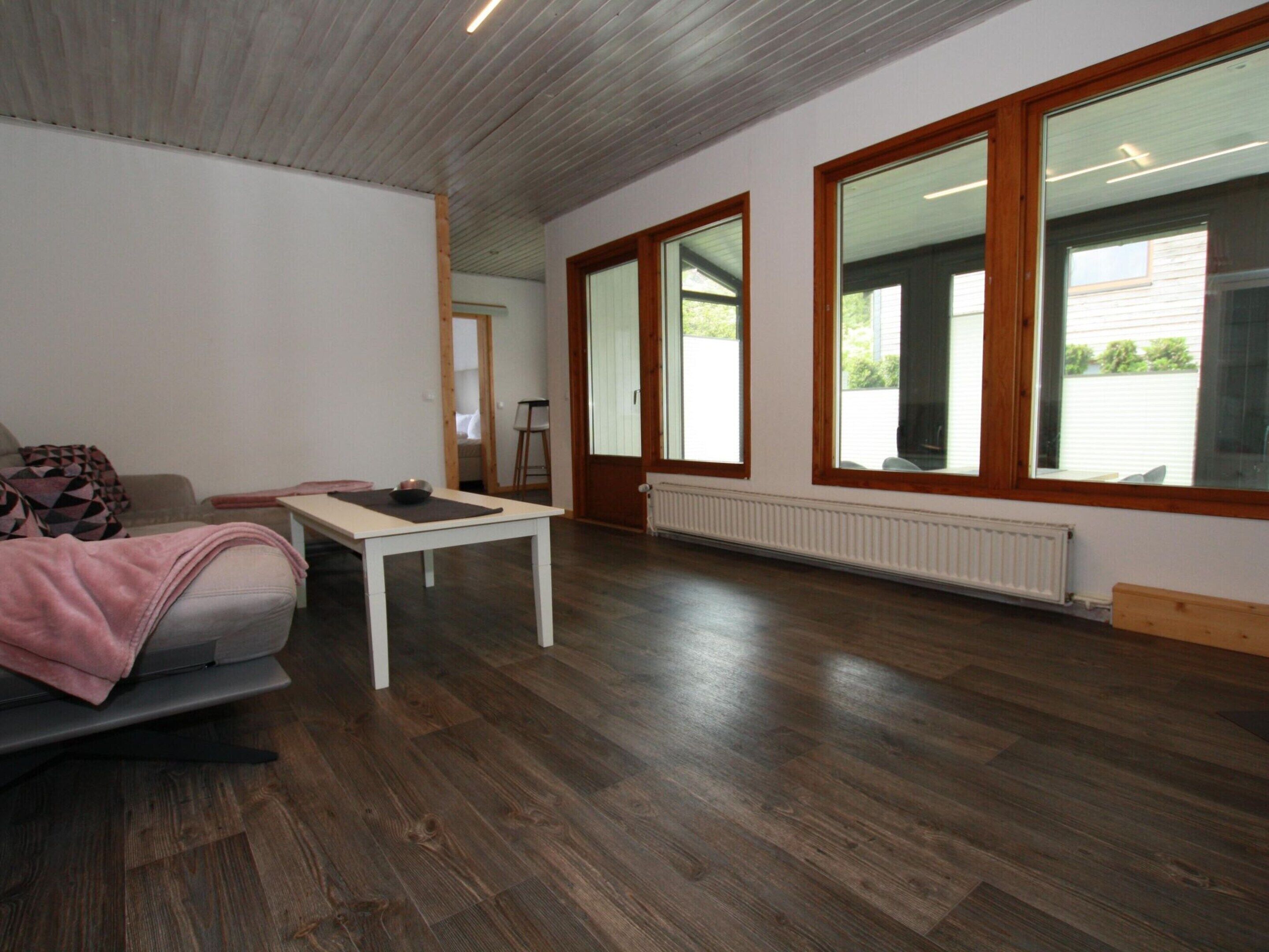 Ein modernes Wohnzimmer mit einer Couch, einem Couchtisch und großen Fenstern.
