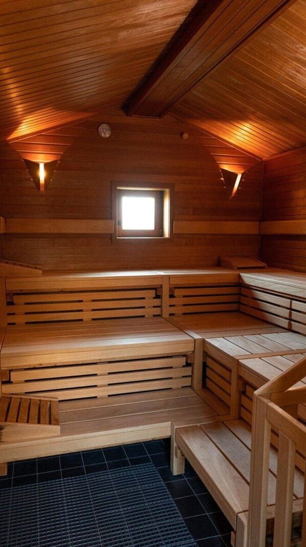 A sauna with wooden benches and a small window. - Beech Resort Boltenhagen (Boltenhagen)
