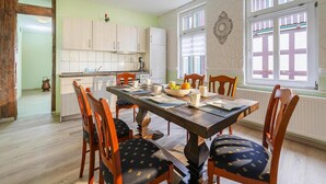 A dining area with a wooden table and chairs, a bowl of fruit, and a coffee cup. - Ferienwohnung Fachwerktraum, Wernigerode (Wernigerode)