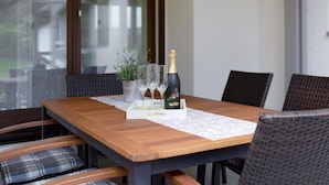 A wooden dining table with four chairs, a bottle of champagne, and three glasses on a placemat. - Apartment in Sallneck Near Nonnenmattweiher Lake (Kleines Wiesental)