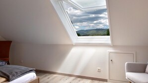 A room with a sloped ceiling, a skylight, a bed, a chair, and a wardrobe. - Apartment in Sallneck Near Nonnenmattweiher Lake (Kleines Wiesental)