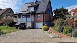 A two-story house with a sloped roof, a garage, and a gravel driveway. - Ferienwohnung, Gromitz (Groemitz)