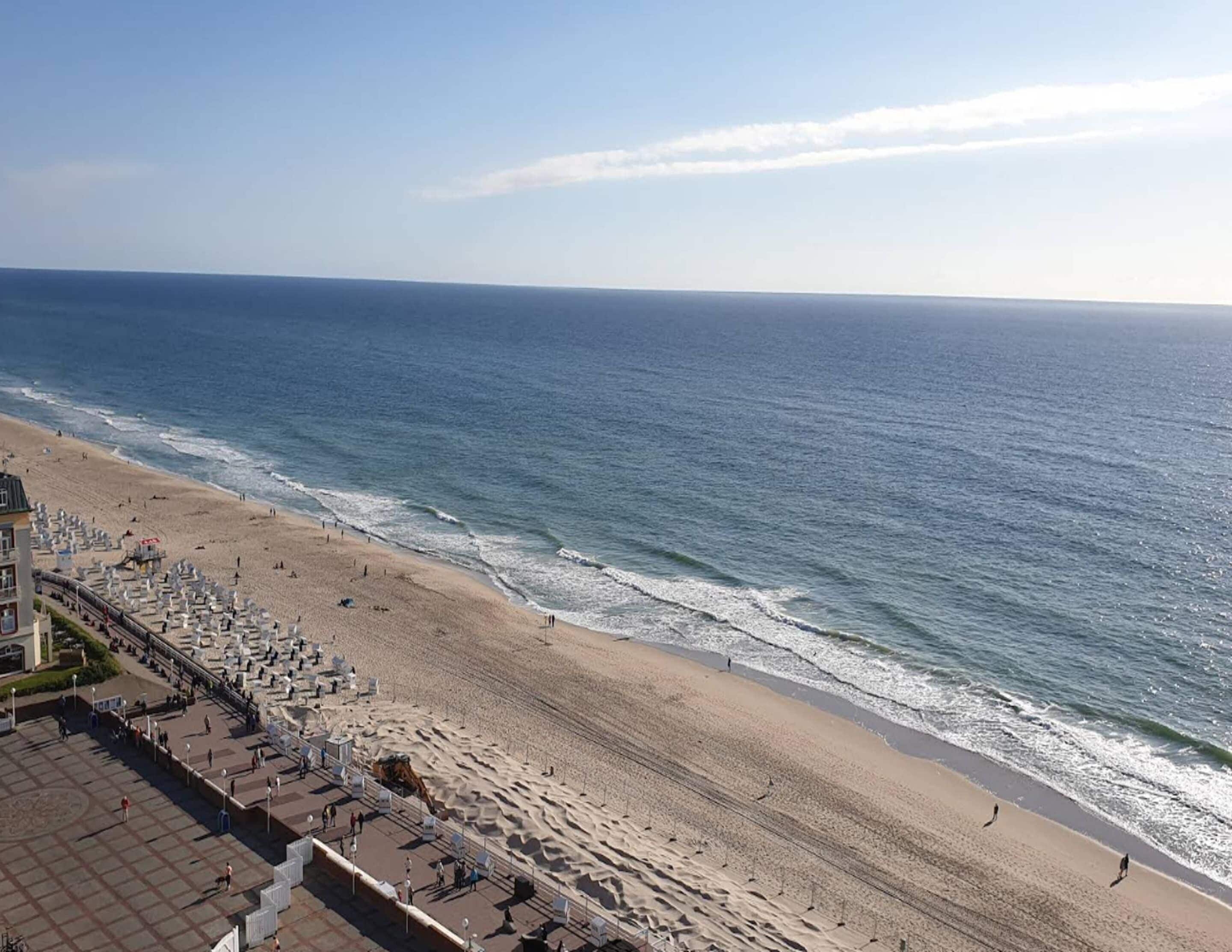A beach with a promenade, benches, and a lifeguard tower.