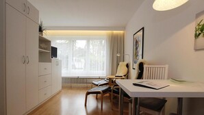 A modern, well-lit room with a dining table, chairs, a sofa, and a TV. - Ferienwohnung in Westerland auf Sylt (Sylt)