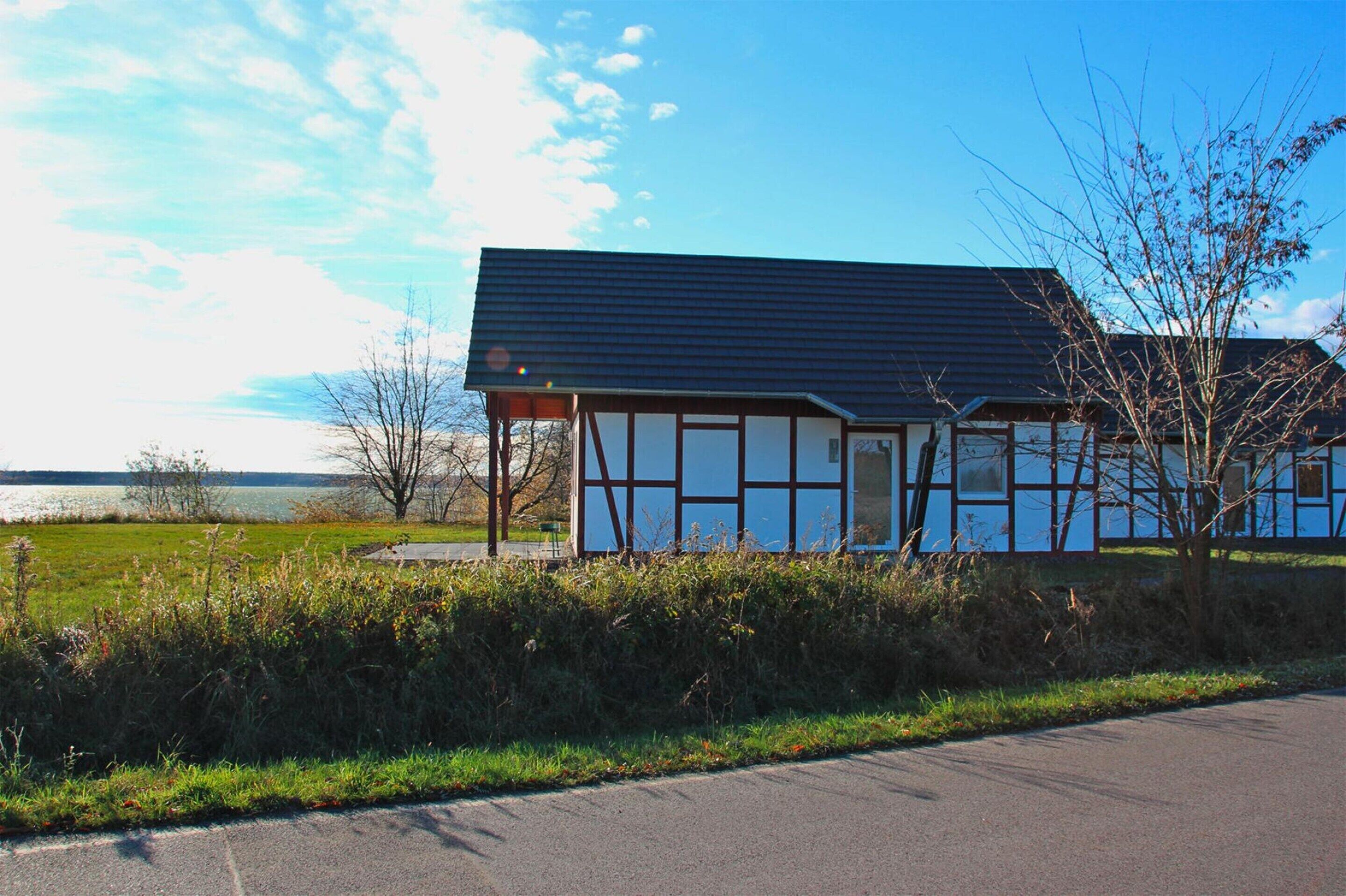 A modern building with a dark roof and white walls, situated near a body of water.