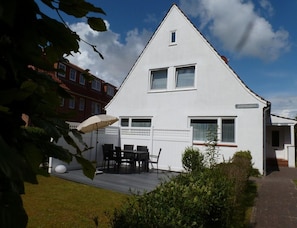 A white two-story house with a visible balcony, a small window, and a door. - Ferienwohnung, St. Peter-ording (St. Peter-Ording)