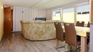 Um espaço de estar compacto com um sofá, uma mesa de jantar com cadeiras e uma televisão.