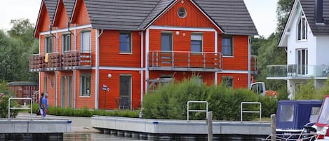 A red multi-story house with balconies, a dock, and a boat.