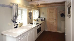 A kitchen with white cabinets, a double sink, and a wooden ceiling.