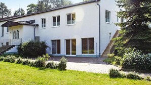 A two-story building with a white exterior, a covered porch, and a staircase leading to the upper floor. - Appartementhaus Seeperle, Sommersdorf (Sommersdorf)
