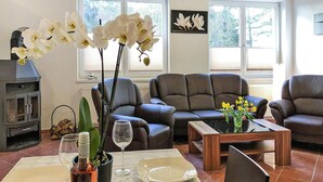 A living room with a fireplace, two sofas, a coffee table, and a dining table set for two. - Appartementhaus Seeperle, Sommersdorf (Sommersdorf)