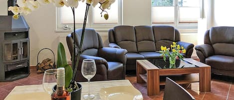 A living room with a fireplace, two sofas, a coffee table, and a dining table set for two.