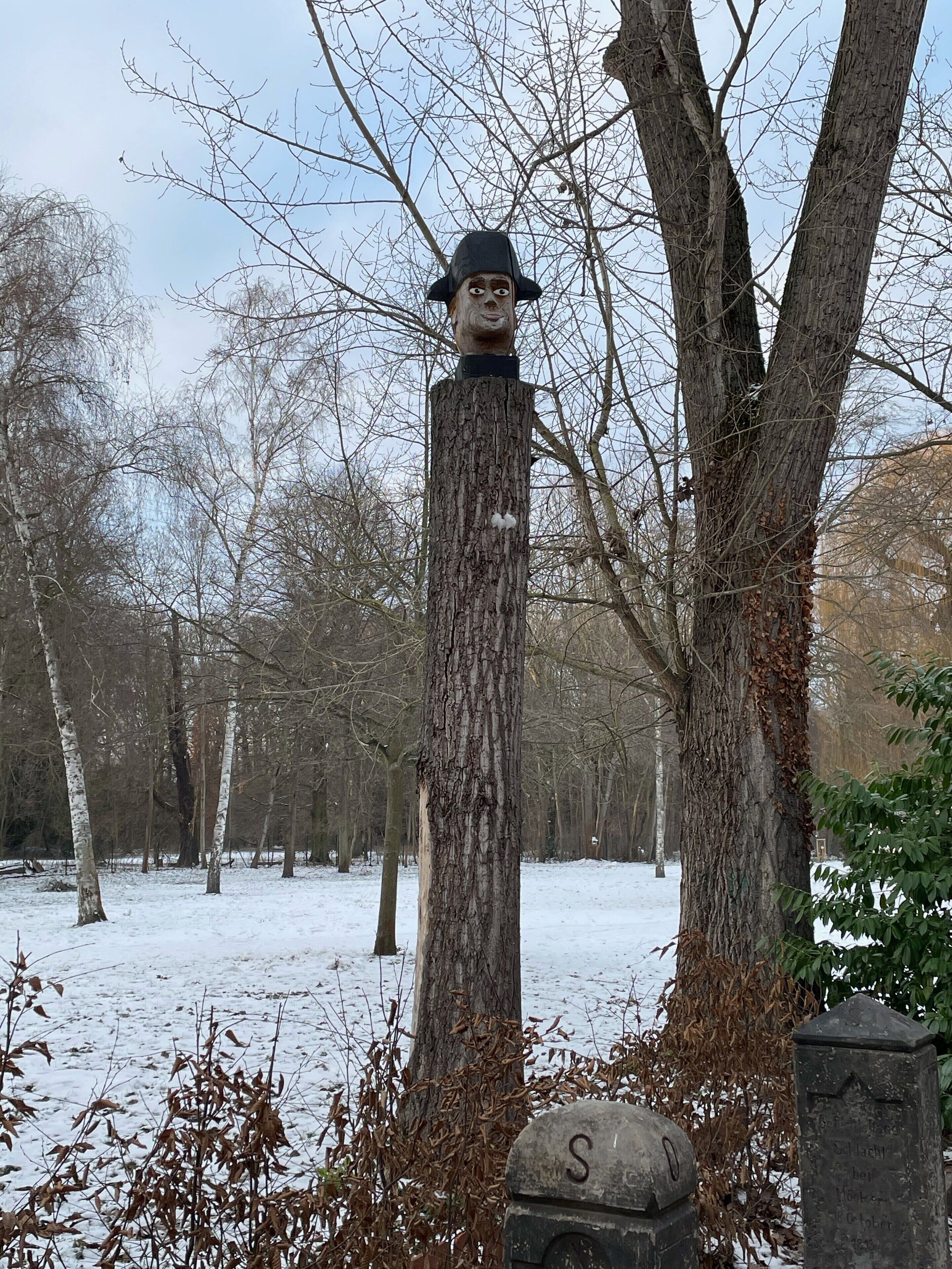 Ein verschneites Freigelände mit einem Holzpfosten und einem Steinschild.
