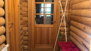 A log cabin interior with a wooden door, a small bench, and a radiator. - Ferienhaus, Wiefelstede-lehe (Wiefelstede)
