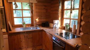 A compact kitchen with wooden cabinets, a sink, a coffee maker, and a dishwasher. - Ferienhaus, Wiefelstede-lehe (Wiefelstede)