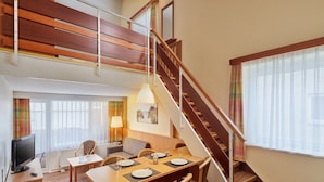 A modern hotel room with a dining area, a staircase, and a television. - Ferien- und Freizeitpark Weissenhauser Strand (Wangels)