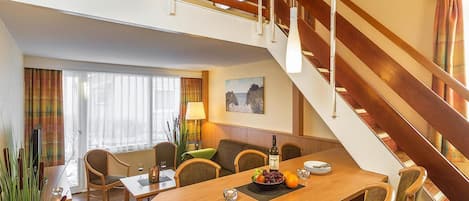 A hotel room with a dining area, a staircase, and a view of the outdoors.