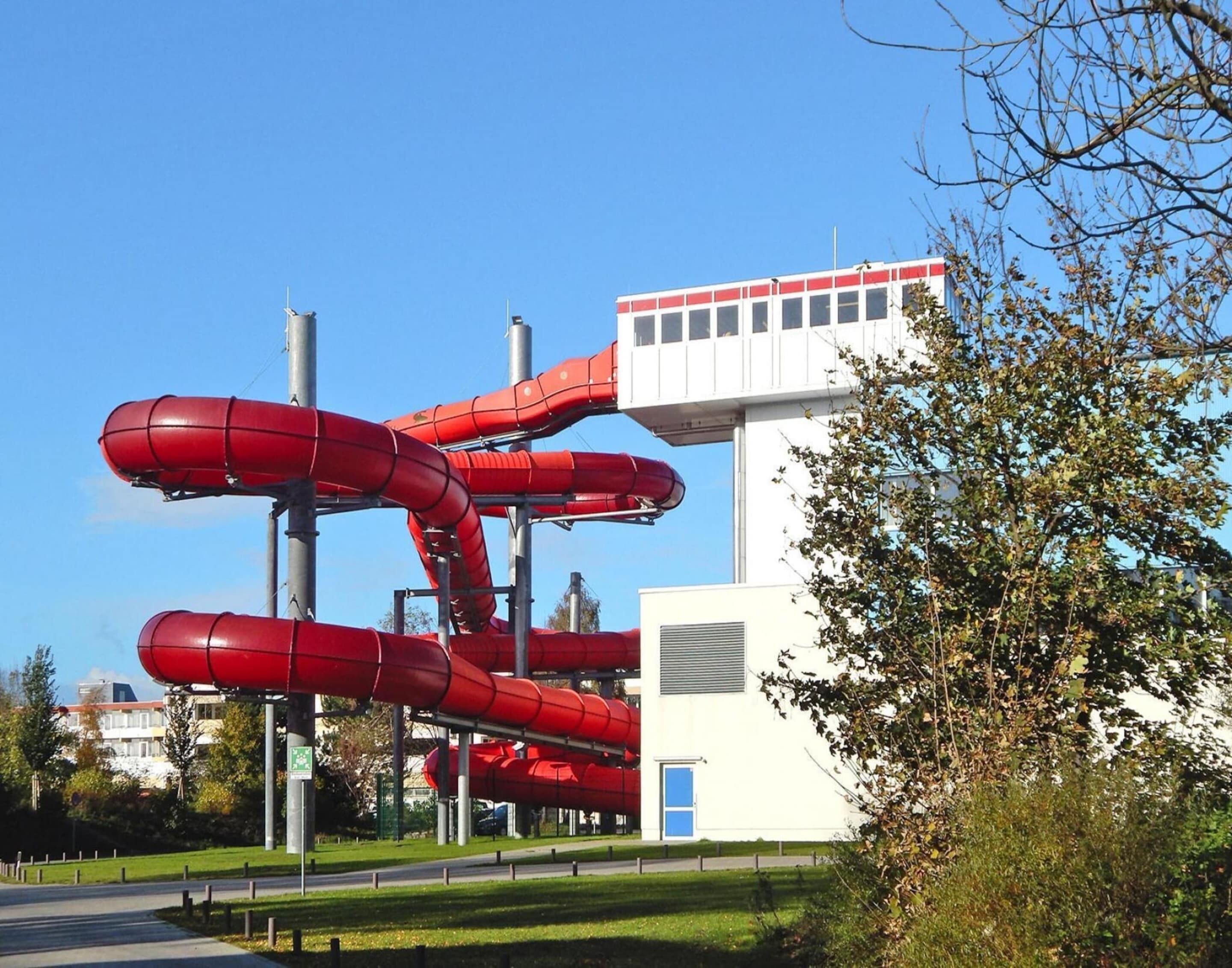 A building with a white exterior and a red water slide structure attached to it.