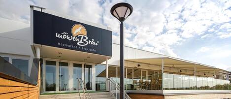 A modern restaurant with a sign reading "MöwenBräu Restaurant - Braustube" and a staircase leading to an outdoor seating area.