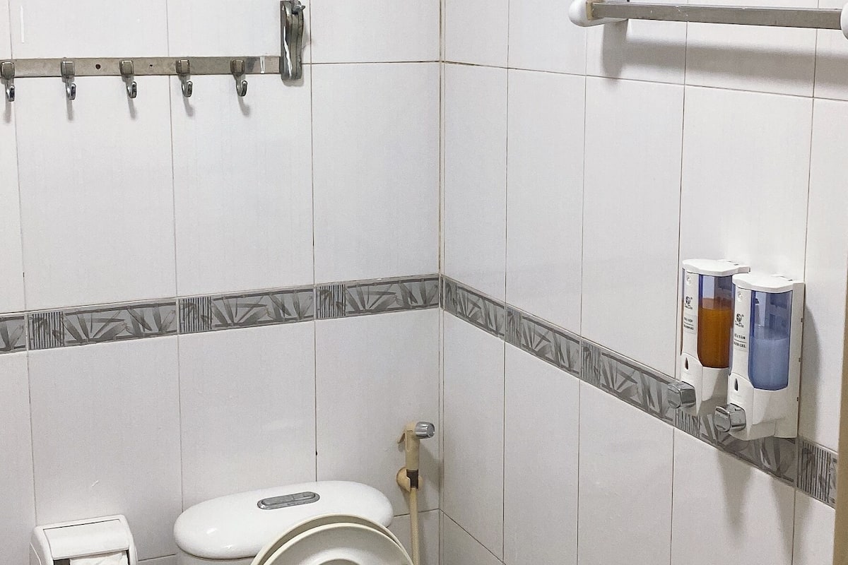 A small, clean bathroom with a toilet, a sink, a hand dryer, and a paper towel dispenser.