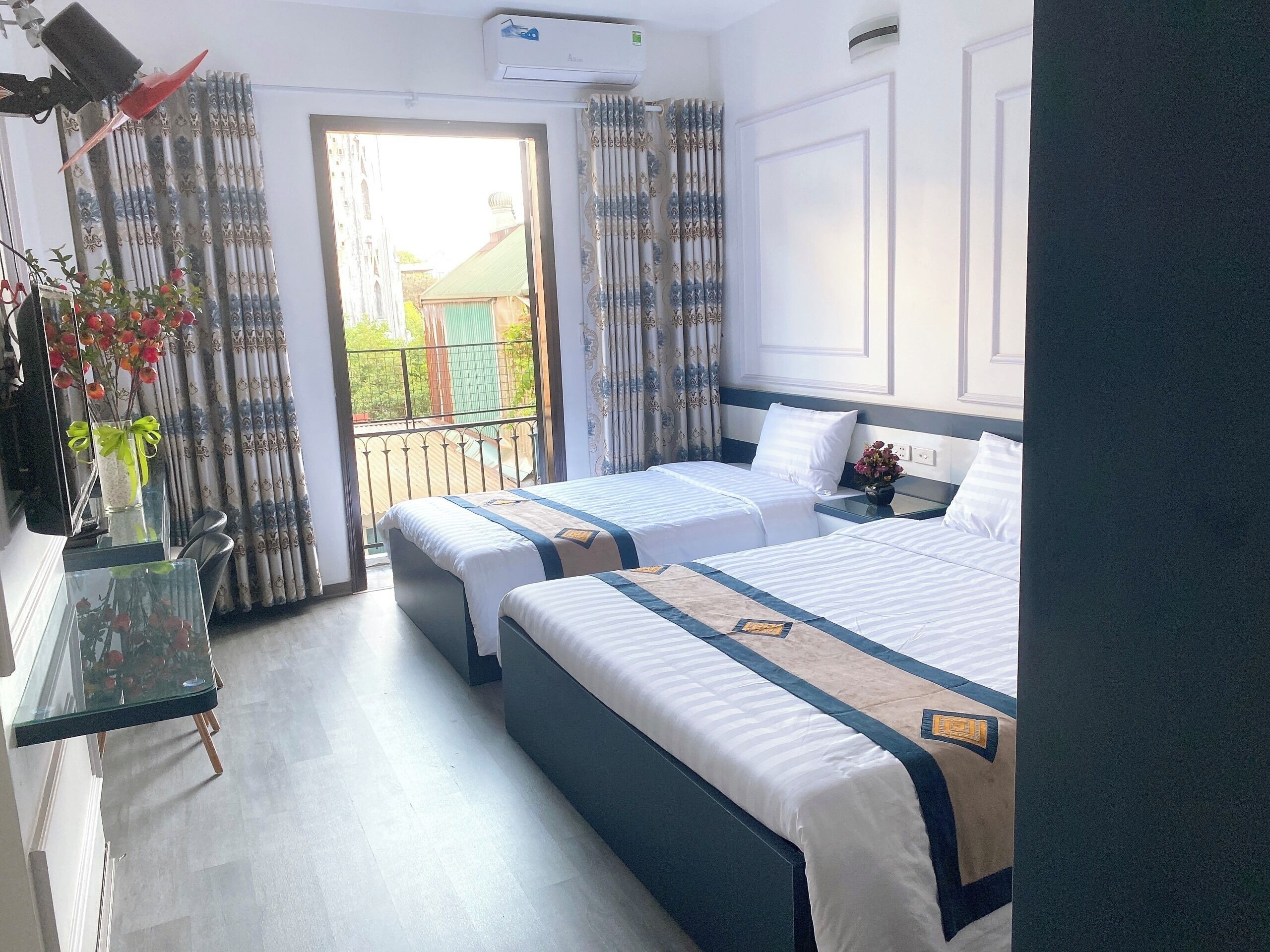 Quarto de hotel com duas camas, varanda e vista para edifícios.