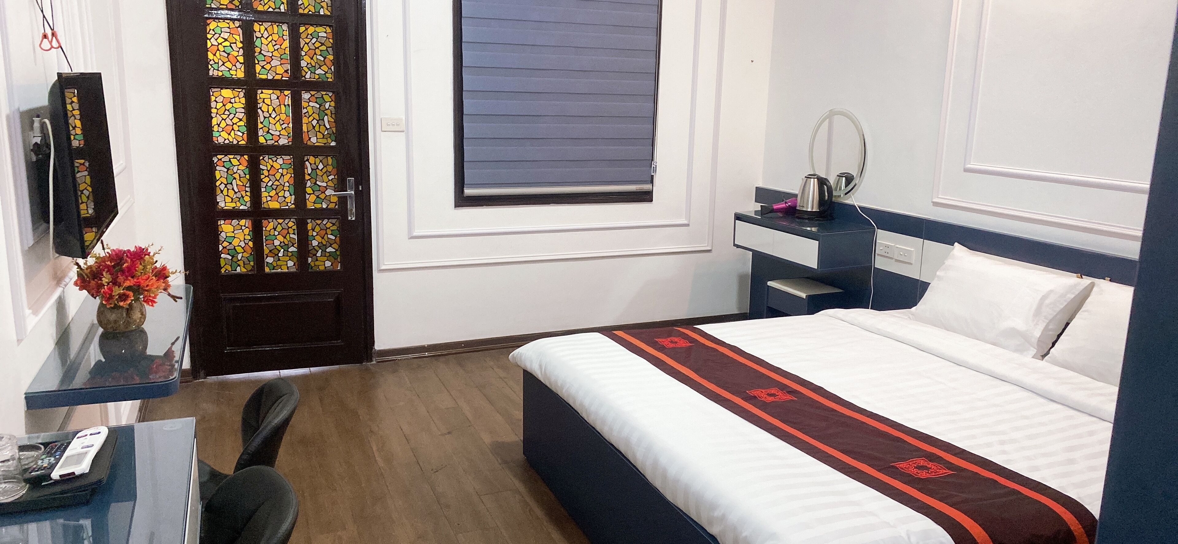 A hotel room with a bed, bedside table, and a mirror.