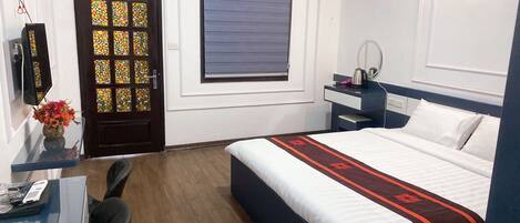 A hotel room with a bed, bedside table, and a mirror.