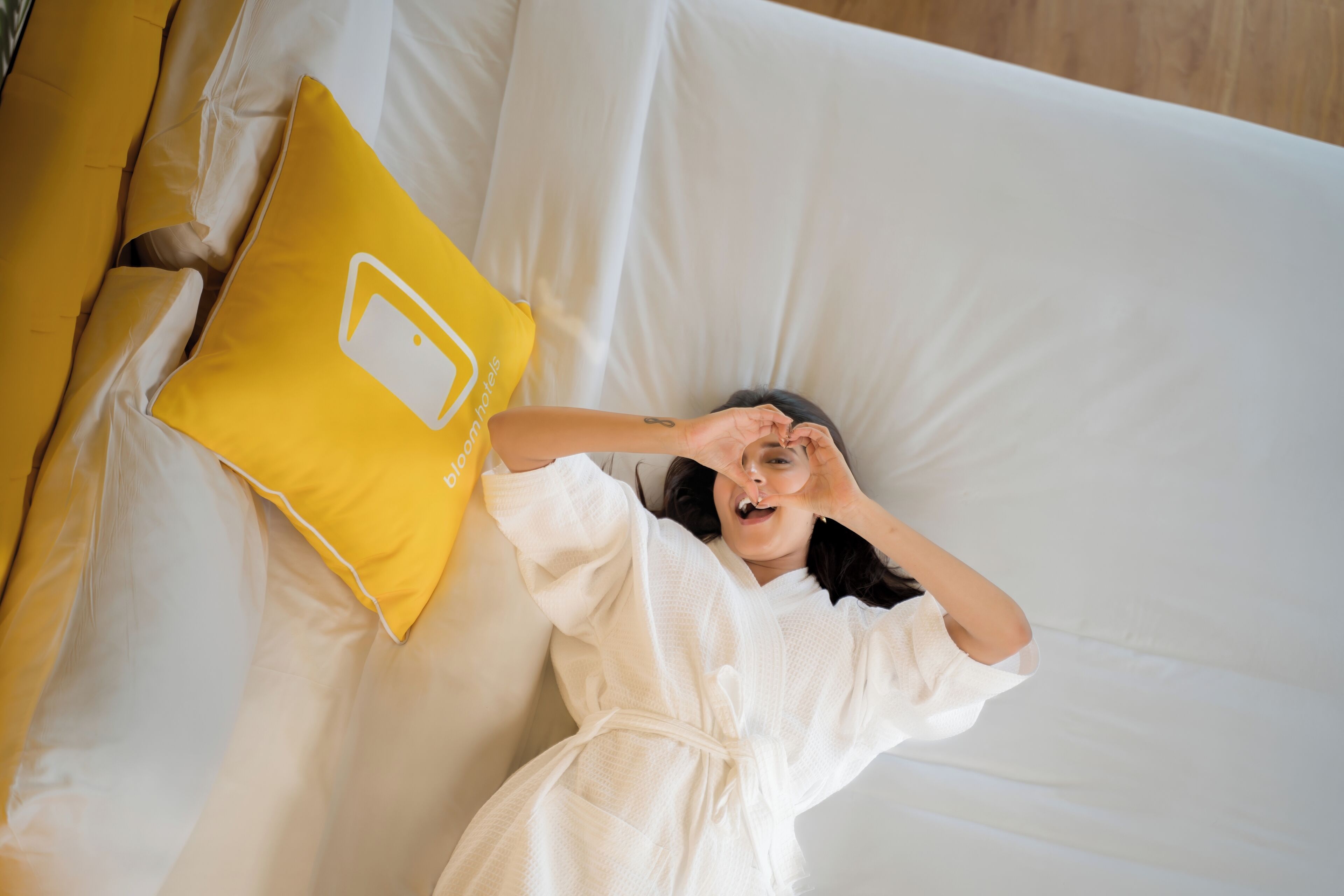 A person lying on a bed with a white and yellow pillow.