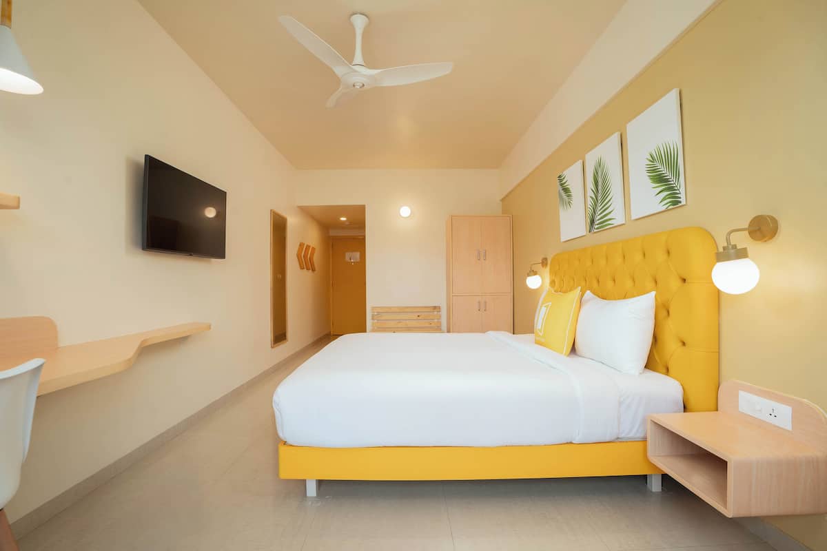 A modern bedroom with a large bed, a ceiling fan, a flat-screen TV, and a wooden nightstand.
