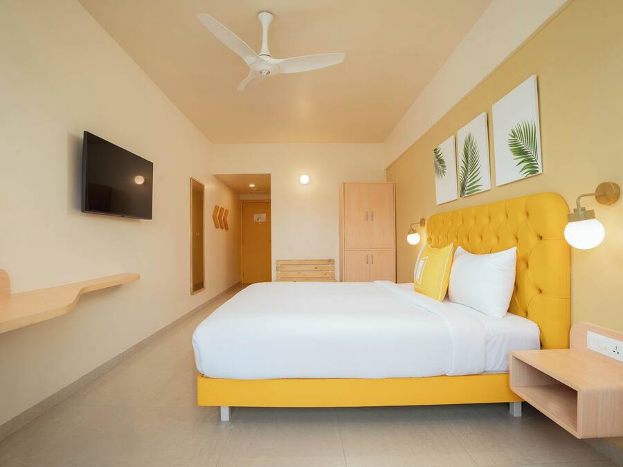 A modern bedroom with a large bed, a ceiling fan, a flat-screen TV, and a wooden nightstand.