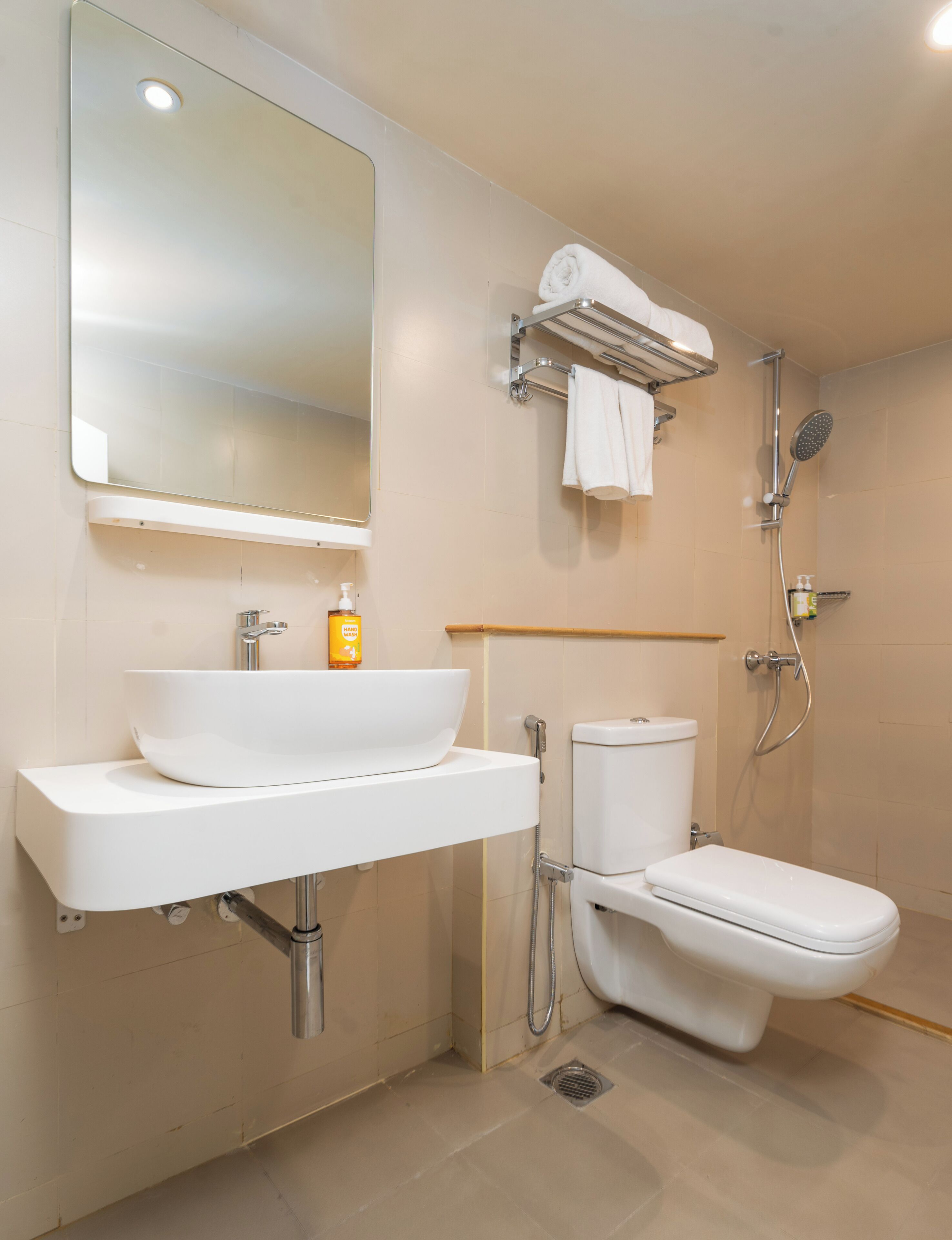 A modern bathroom with a white sink, mirror, toilet, and shower.