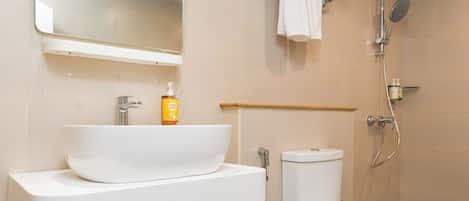 Un baño moderno con lavamanos, espejo, inodoro y ducha blancos.