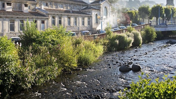 Un edificio tradizionale con una cupola imponente, affiancato da un fiume e un ponte in pietra.