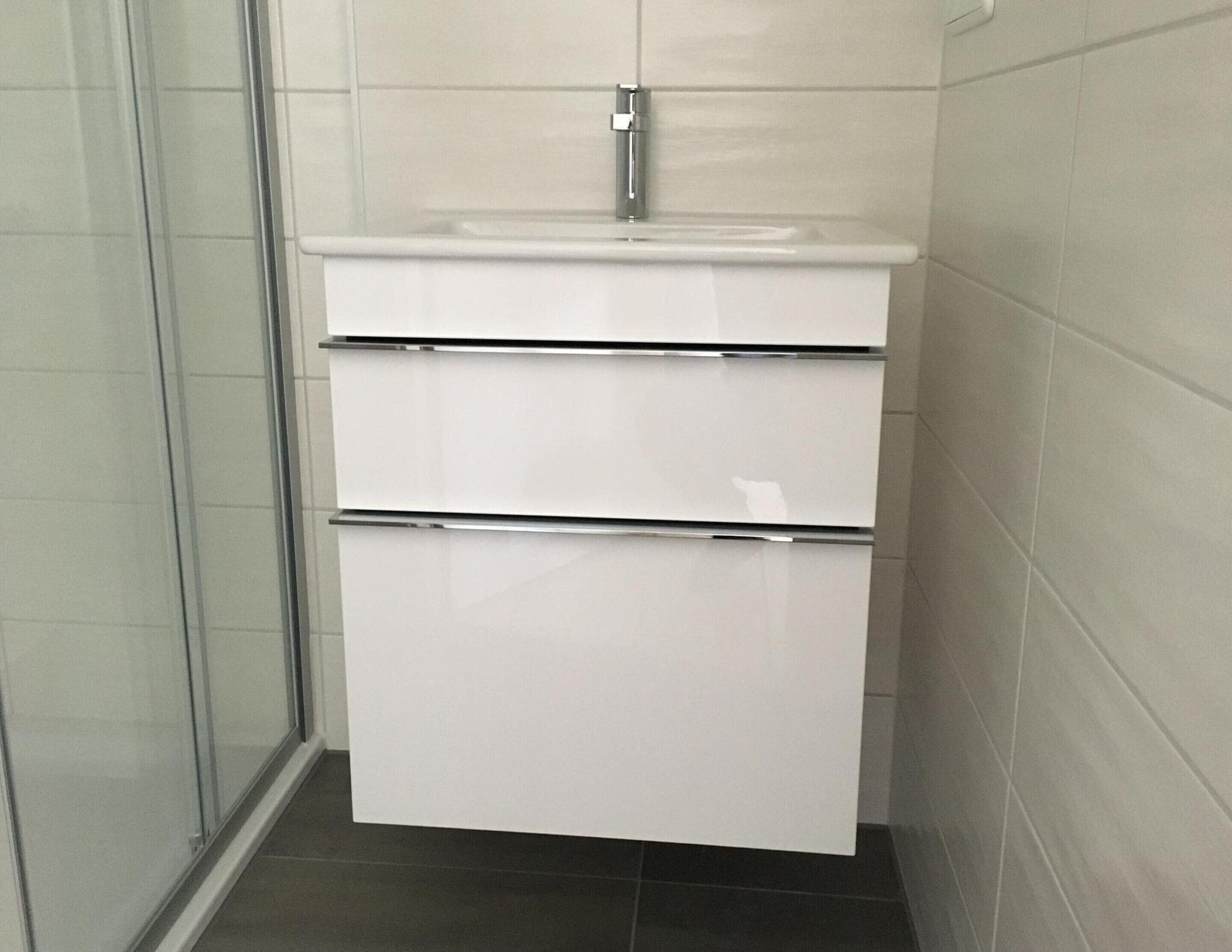 A bathroom with a white sink, two drawers, and a mirror.