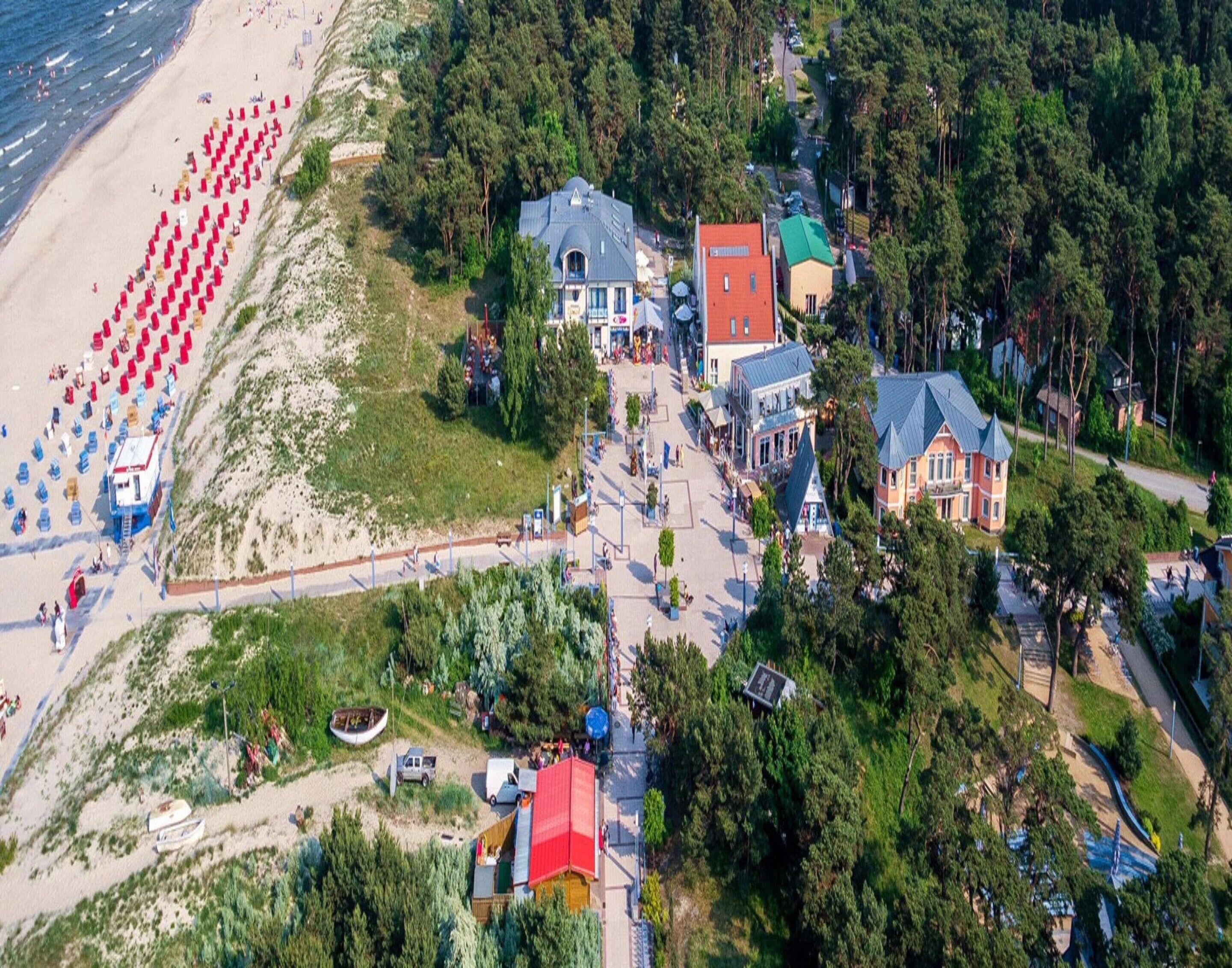An aerial view of a coastal area with a beach, several buildings, and a small boat.