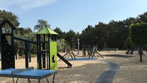 Ένας παιδότοπος με κατασκευές για αναρρίχηση, τσουλήθρες και μια αμμοδόχο.