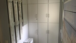 Ένα δωμάτιο με μια ντουλάπα, ένα μικρό ξύλινο παγκάκι και έναν καθρέφτη.