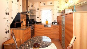 A compact kitchen with wooden cabinets, a granite countertop, and a built-in oven. - Holiday Home in Storkow Near Storkow Castle (Storkow)