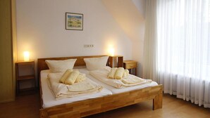Un lit double avec une tête de lit et un pied de lit en bois, deux tables de chevet et un tableau accroché au mur.