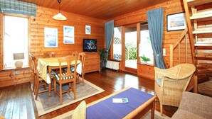 A wooden cabin interior with a dining area, a television, and a staircase. - Ferienhaus in Hasselfelde (Oberharz am Brocken)